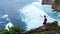 Successful young man silhouette standing on ocean cliff aerial raising arms happiness joy freedom concept