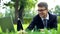 Successful young manager lying on green grass, smiling and chatting on laptop