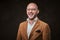 Successfull and smiling bald businessman posing in a studio wearing stylish velvet jacket, white shirt and glasses