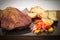 Succulent thick juicy portions of grilled fillet steak served with roasted potatoes and peppers on black granite board