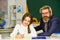 Such an interesting lesson. Little girl and man at blackboard. knowledge day concept. child with teacher in classroom at