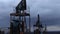 Sucker rod pumps are working and pumping oil against the backdrop of the evening sky. Oil well service