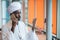 Sudanese business man in traditional outfit using mobile phone in office