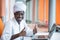 Sudanese business man in traditional outfit using mobile phone in office