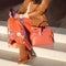 Suede boots on women`s legs. Sunglasses in the hands. Elegant bag with bow. Close-up
