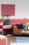 Suede burgundy and pastel pink commode with black vase with green leaf in classy living room interior