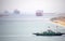 Suez Canal zone. Ship convoy in the distant desert haze. A local ferry between the east and west bank in foreground.