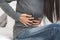 Suffer from stomach ache. asian young woman sitting on the bed feeling pain in stomach