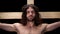 Suffering crucified messiah looking camera on black background, religious faith