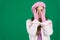 suffering experiences sadness girl with two hands wearing knitted pink gloves covers her face on a green background