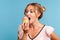 Sugar addiction. Portrait of hungry blonde young adult woman in dress biting delicious cake, looking with desire to eat sweet