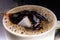 A sugar cube dropped into a cup with black coffee. Falling sugar into a warm drink