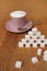 Sugar cubes made from sugar cubes, full of pink tea cup and saucer, refined slices, the concept of excess sugar consumption,