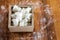 Sugar Cubes in Square Shaped Bowl with Unrefined Sugar spill over in Wooden Background.