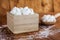 Sugar Cubes in Square Shaped Bowl with Unrefined Sugar spill over in Wooden Background.