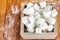 Sugar Cubes in Square Shaped Bowl with Unrefined Sugar spill over in Wooden Background.