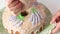 Sugar cupcake. Woman draws lavender flowers on a cupcake. With icing, using a pastry bag. Shot in close-up from above