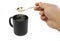 Sugar falling from spoon in man hand into a cup