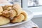 Sugar-frosted croissants from a cottage cheese dough on a white plate on a table with linen tablecloth. Tea snack for breakfast