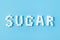 Sugar inscription made of sugar cubes on trendy blue background