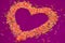 Sugar long baking sprinkles in the shape of a heart on a purple background, concept and background for Valentine Day