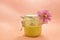 Sugar paste for depilation. Shugaring. Removing hair. Cosmetics. Honey in jar with flower on Living Coral background