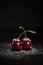 Sugar poured over fresh red cherry against dark background with copy space