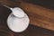 Sugar poured into a steel bowl on a wooden table.