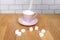 Sugar pouring in a pink tea cup and saucer, refined slices on a wooden table, concept of excess sugar consumption, diabetic, close