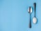 Sugar-replacement tablet of stevia and sugar in tea spoons lying in opposite directions on light blue paper background