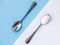 Sugar-replacement tablet and sugar in tea spoons lying in opposite diagonal directions on blue white background.