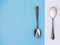 Sugar-replacement tablet and sugar in tea spoons lying in opposite directions on blue white background.