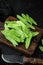 Sugar snap peas, raw ripe baby pods, on wooden cutting board, on black wooden background