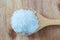 Sugar in a wooden spoon on wood background-closeup