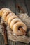 Sugared mini donuts lined up on a cinnamon stick on a wooden table