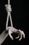 Suicide and depression topic: human hand hanging on rope loop on a black background