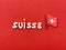 Suisse, Switzerland text composed with wooden letters over red wooden board