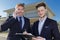 suited men with clipboard and smartphone outside residential property