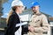 Suited woman shaking hands with workman by residential property