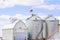 Sukup Brand Twin Silo Grain Bins Next to White Barn