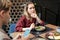 Sulky young blond woman in maroon dress eating salad and expressing sadness