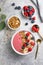 Summer acai smoothie bowls with raspberries, banana, blueberries, and granola on gray concrete background. Breakfast bowl with