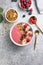 Summer acai smoothie bowls with raspberries, banana, blueberries, and granola on gray concrete background. Breakfast bowl with