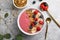 Summer acai smoothie bowls with raspberries, banana, blueberries, and granola on gray concrete background. Breakfast bowl with