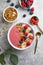 Summer acai smoothie bowls with raspberries, banana, blueberries, and granola on gray concrete background. Breakfast bowl with