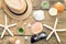Summer accessories as hat, shells, sun glasses and candles on wooden and sandy background