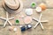 Summer accessories as hat, shells, sun glasses and candles on wooden and sandy background