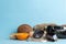 Summer accessories with coconut, orange and shells, photo camera on a  bright blue background. free space