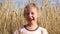 Summer baby girl outdoors video. European girl with blond hair smiles against the background of a field with wheat and rye in