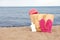 Summer bag with slippers, beach towel and sunscreen on sand near sea, space for text